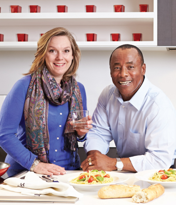 Two smiling patients with plates of pasta and bread in front of them
